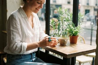 Femme admirant une bague en pierre naturelle dans un café parisien