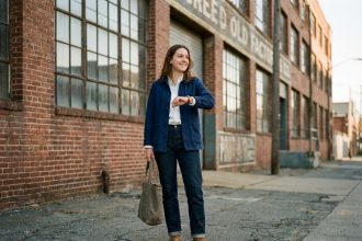 Jeune femme souriante en veste de travail dans une usine urbaine